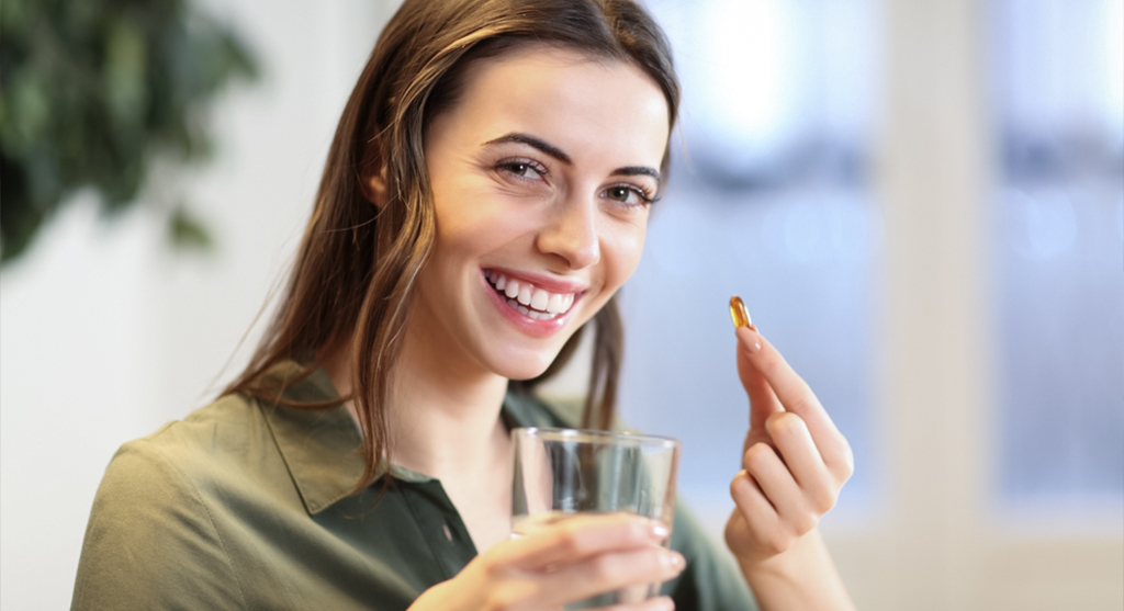 happy woman showing vitamin pill ready